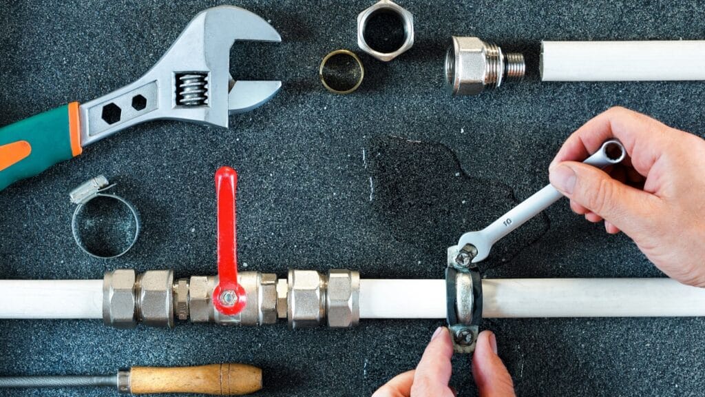 Plumber repairing a pipe valve with an adjustable wrench in Carlisle