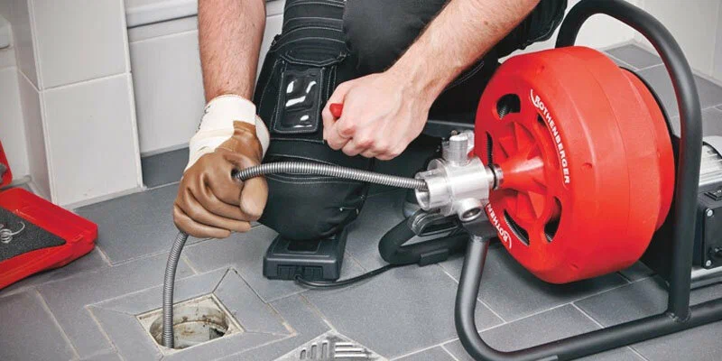 Plumber using a drain-cleaning machine in Carlisle