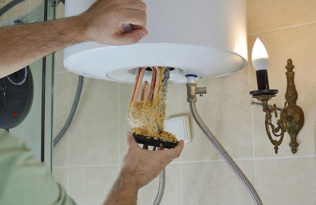 Technician removing mineral buildup from a water heater in Carlisle