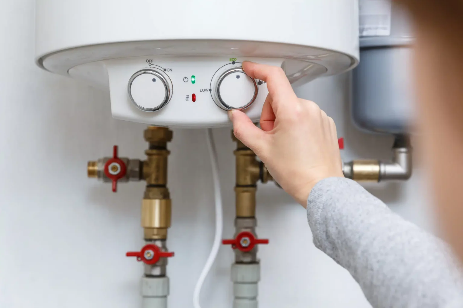 Homeowner adjusting the temperature controls on a water heater in Carlisle